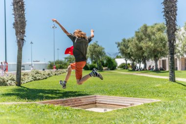 Lisboa, Portekiz - 22 Temmuz 2016: Parktaki küçük bir çeşmenin üzerinden atlayan çocuk.