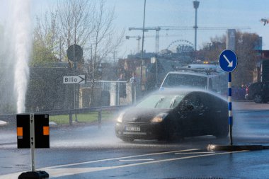 Göteborg, İsveç - 01 Mayıs 2022: Su dolu bir caddeden geçen arabalar büyük bir su sızıntısı tarafından tamamen yıkandı.