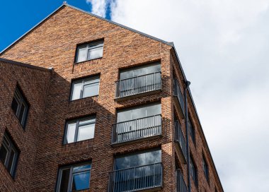 Looking up a tall newly constructed brick apartment building.