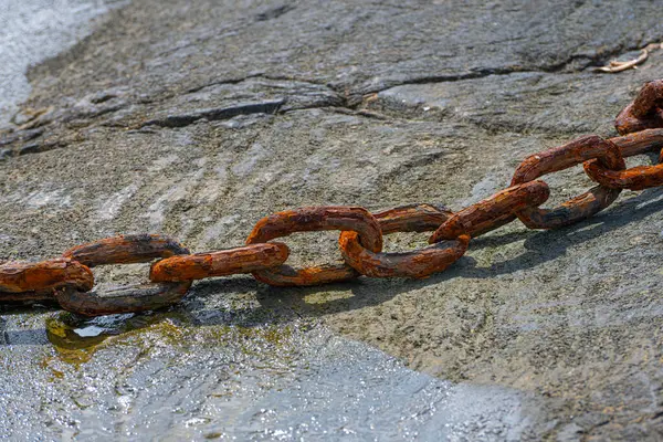 Old rusty metal chain on wet ground.