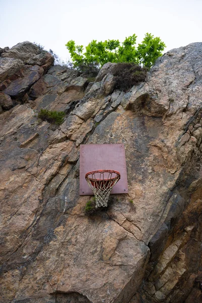 Basket ball basket hanging from a stone cliff face.