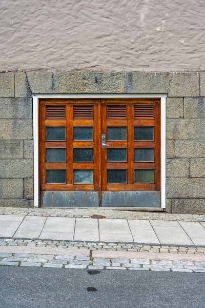 Small wooden service doors by the pavement.