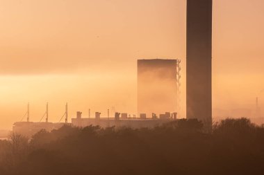 Göteborg, İsveç - 23 Mart 2022: Yerel siste güneşin önündeki uzun baca.
