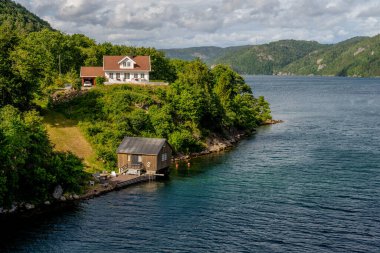 Lyngdal, Norveç - 02 Temmuz 2023: Geleneksel ahşap ev ve deniz kenarındaki kayıkhaneler.