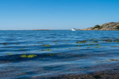 Yazın kayalıkların yanında küçük dalgalı beyaz bir tekne..