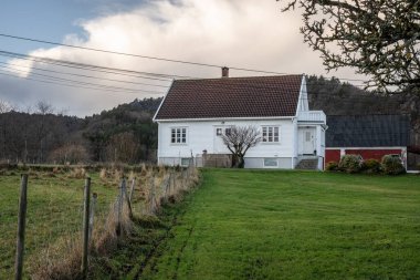 Lindesnes, Norveç - 26 Aralık 2023: Beyaz ahşap ev ve yeşil bahçe.