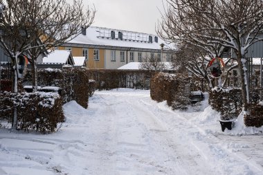 Kışın evler arasında karlı dar bir cadde.