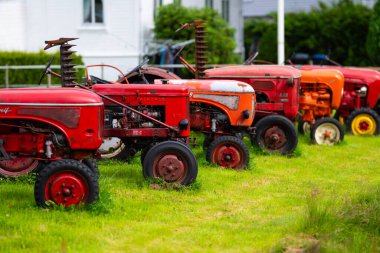 Lyngdal, Norveç - 12 Temmuz 2024: Uzun kırmızı vintage Hanomag ve Porsche traktörleri.