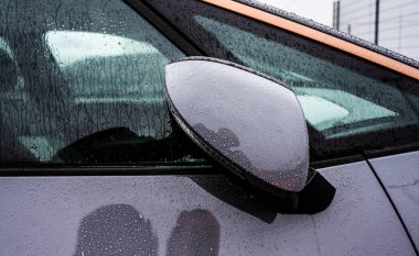 Gri bir arabanın aynasında katlanmış.