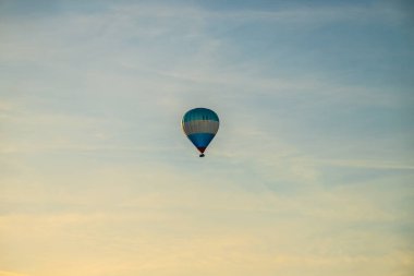 Akşam güneşinde mavi beyaz ve kırmızı sıcak hava balonu