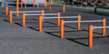 Açık hava spor salonu ve parlak turuncu çalışma çubukları.