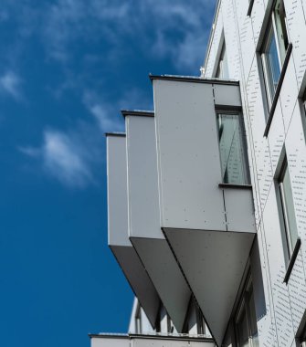 Mavi gökyüzüne karşı metal balkonları olan modern bina