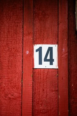 Beyaz plakette kırmızı ahşap bir evde 14 yazıyor.