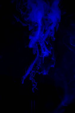 Koyu arkaplanda dönen mavi duman izleri