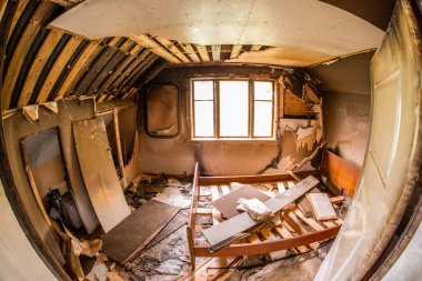 Kırık mobilyalar ve döküntülerle terk edilmiş bir oda.