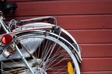 Kırmızı ahşap bir duvarın yanına park edilmiş iki bisiklet.
