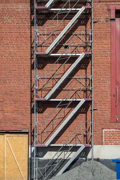 Kırmızı tuğla duvardaki zik-zag iskele merdivenleri.