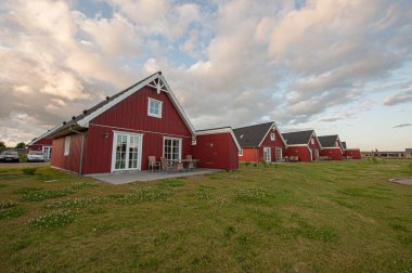 Çimen tarlasında kırmızı ahşap kulübeler.