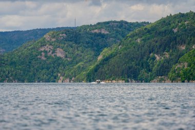 Derin bir fiyortta hızlı bir tekne seyrediyor.