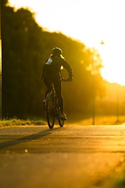 Bisikletçi sabah güneşinde işe gidiyor.