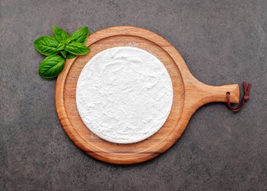 Pizza dough in wooden pizza platter set up on dark concrete. Pizza tray on dark concrete background flat lay and copy space.