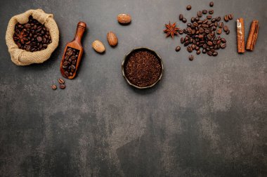 Kahve tozu ve lezzetli malzemelerle kavrulmuş kahve çekirdekleri koyu taşlı arka planda lezzetli kahve yapmak için..