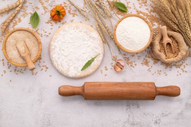 Buğday kulaklı ev yapımı pizza hamuru, buğday unu ve buğday taneleri için malzemeler beyaz beton arka planda..