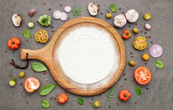 stock image The ingredients for homemade pizza set up on dark stone background.