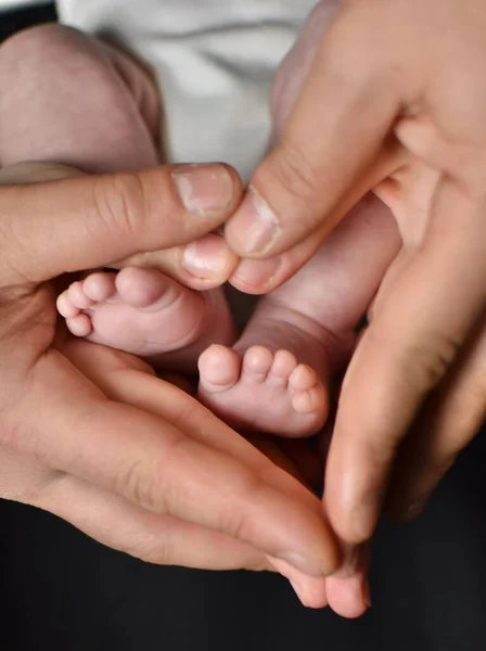 お母さんとお父さんの掌中に生まれたばかりの赤ちゃんの足 — ストック写真