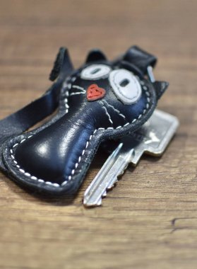 Deri anahtarlık kedi ve anahtarlar ahşap masada.