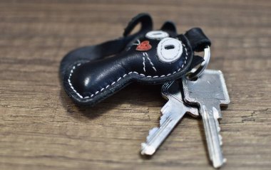 Deri anahtarlık kedi ve anahtarlar ahşap masada.