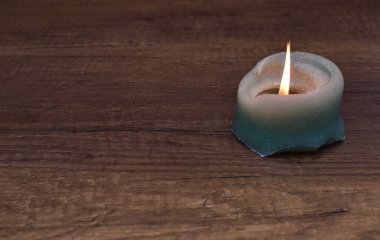 Yanan bir mum ahşap kahverengi bir masanın üzerinde duruyor.