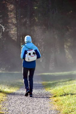 a slender woman in sportswear and with a backpack goes to the forest