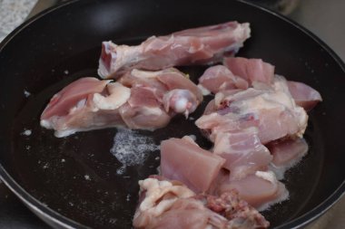 chicken meat is fried in a black pan