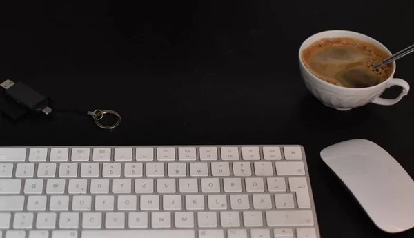 a cup of coffee on the desktop, a keyboard, an adapter, and a computer mouse