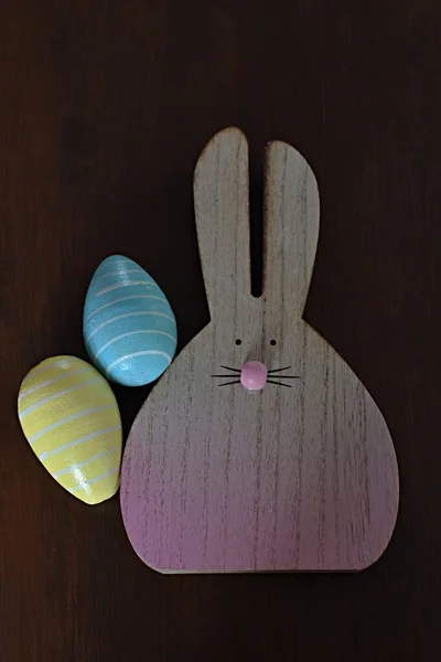 用复活节彩蛋和野兔做成的木制雕像放在木制桌子上 — 图库照片