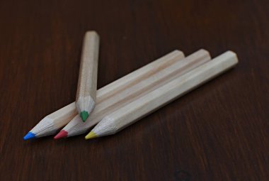 Tahta bir masada dört renkli kalem.