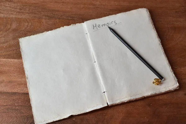 handmade paper notepad with writing memoirs and a simple pencil on a wooden table