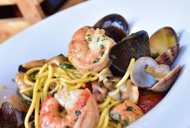 Beyaz tabakta karides ve kabuklu spagetti.