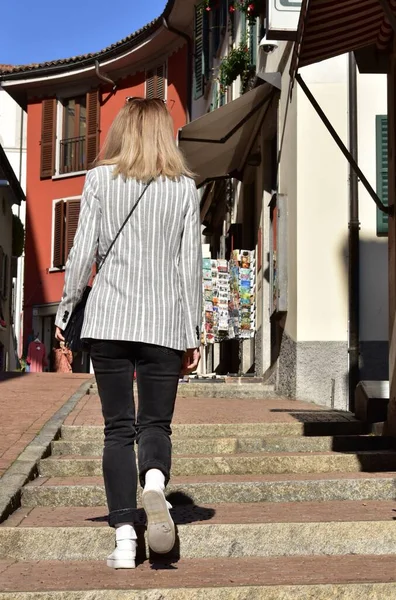 縞模様のジャケットを着た女性がスイスのルガーノの狭い通りを歩いています — ストック写真