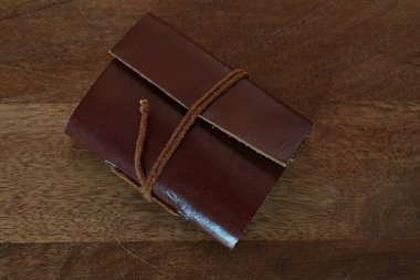 Tahta bir masanın üzerinde deri kaplı küçük bir defter.