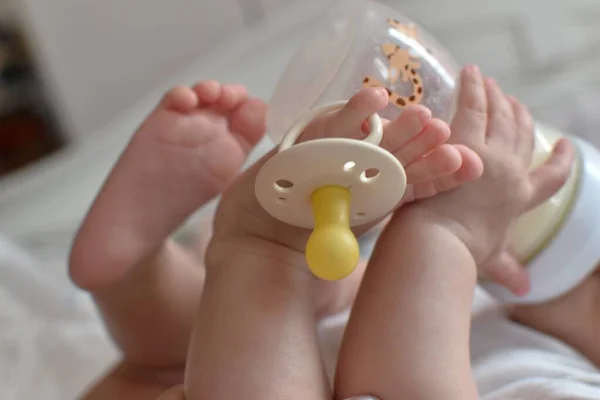 Ребенок Пьет Молоко Бутылки Поднятыми Ногами Держит Соску Ноге — стоковое фото