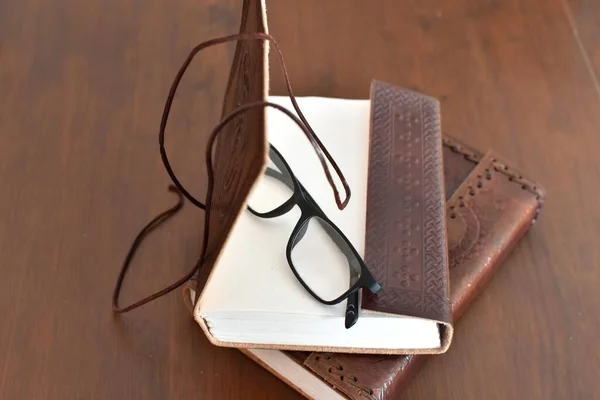 two handmade notebooks in leather cover and reading glasses
