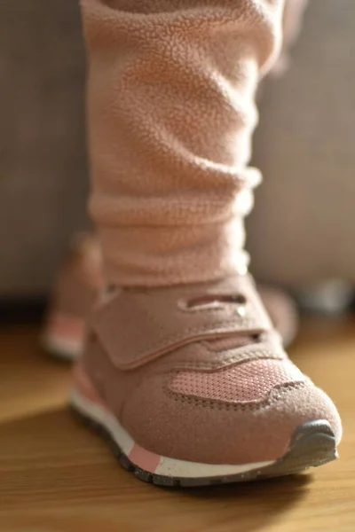 baby stands in sports pink sneakers