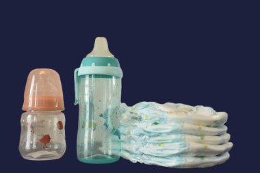 Beslenmek için iki şişe ve siyah arka planda bir bebek için bebek bezi.