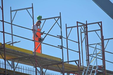 Berlin Almanya 15.05.2024, inşaat alanında çalışan bir erkek. Elinde akıllı bir telefon var.