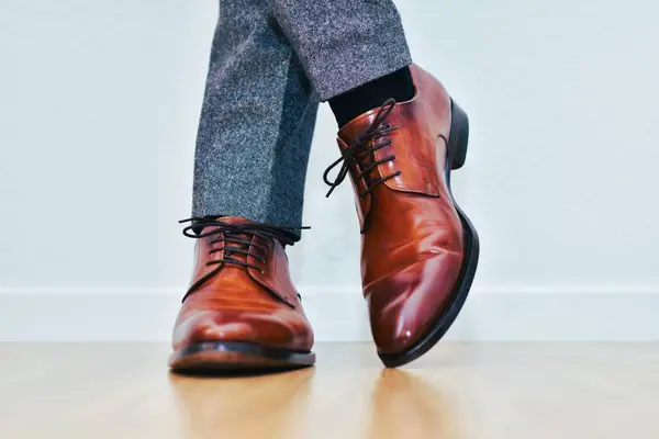 Gri, klasik pantolonlu ve bağcıklı deri kahverengi ayakkabılı bir adam.
