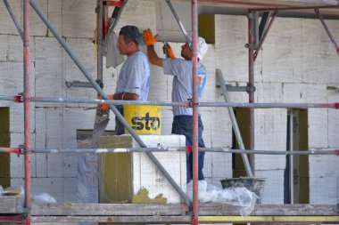 Berlin Almanya 07082024, bir inşaat alanında inşaatçılar bir evin duvarlarına izolasyon malzemesi seriyorlar.