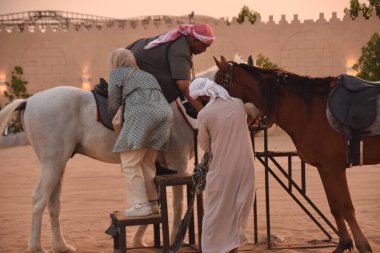 Dubai Birleşik Arap Emirlikleri 07.05.2025, at binme turu, erkek kadının ata binmesine yardım eder