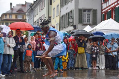 Winterthur İsviçre 06.07. 2025, Afrikalılar geleneksel kıyafetlerle çıplak ayakla dans ediyor Kışın yağmurda İsviçre 'de
